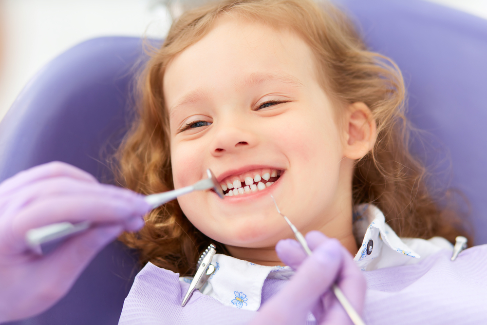 Little girl smiling while undergoing a dental exam