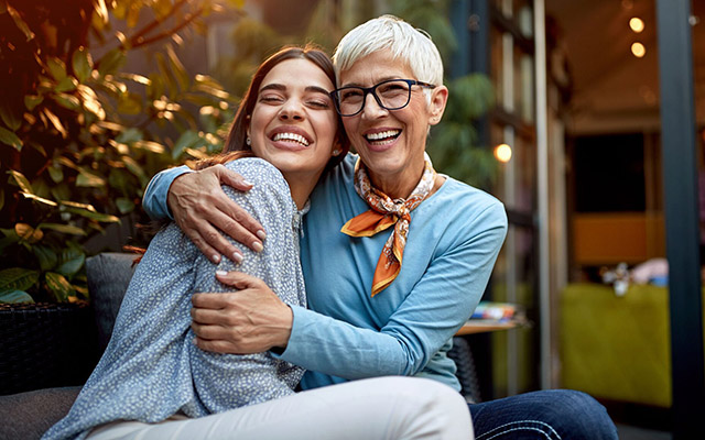 A woman and her mother sit together on a cozy couch, sharing a moment of warmth and connection.