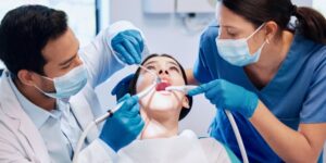 A dentist and dental assistant performing a wisdom teeth extraction on a patient in a dental clinic.